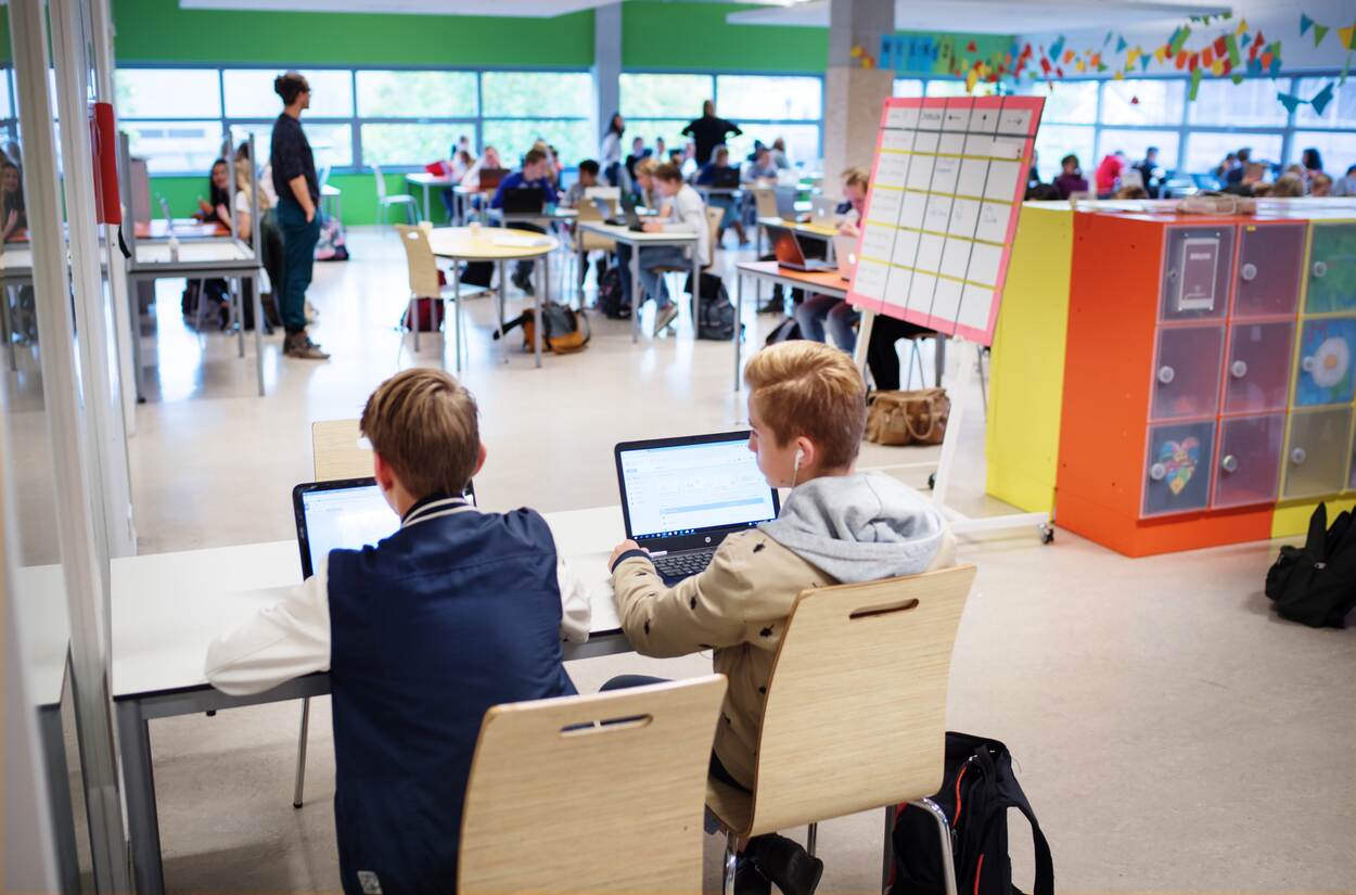 Twee kinderen van achter gefotografeerd die werken op een laptop in een school