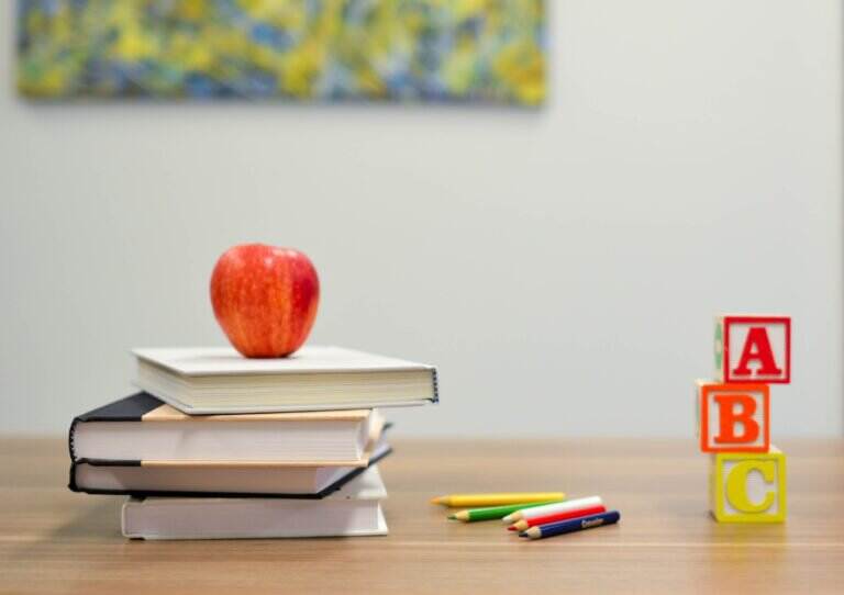 Een foto van opgestapelde boeken met een appel er bovenop
