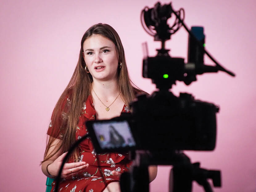 Een jonge vrouw wordt gefilmd door een camera voor een videofragment.