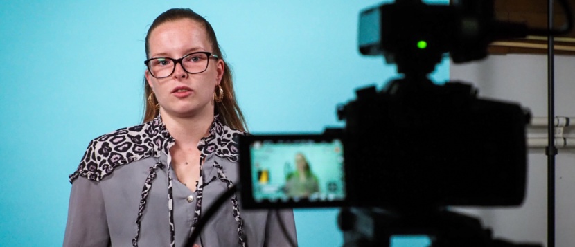 Een jonge vrouw wordt gefilmd door een camera voor een videofragment.