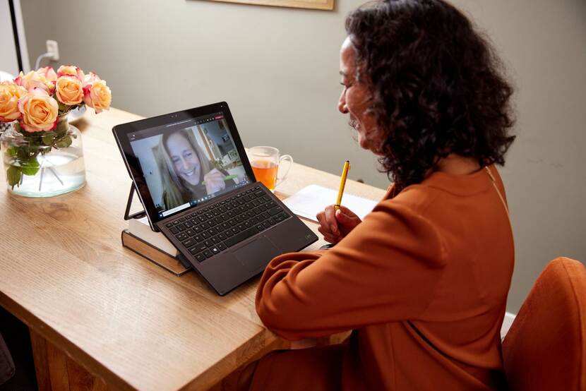 Silvana Bos zit achter een laptop. Sandra Hol is aanwezig op het scherm.