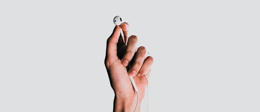 Een hand houdt oortelefoontjes vast.