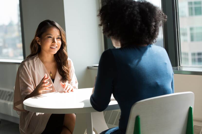 Twee vrouwen van kleur in gesprek aan tafel