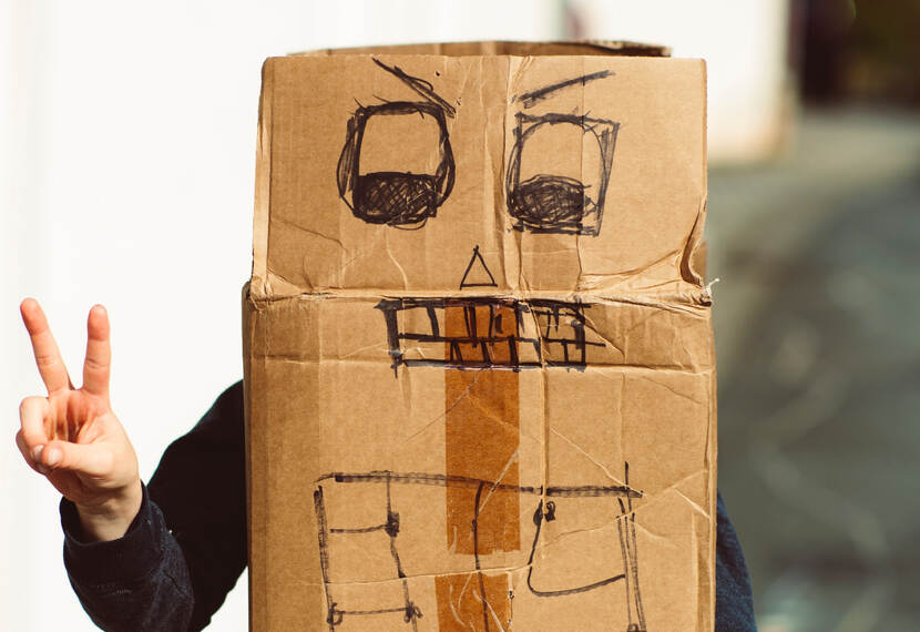 Kind verstopt achter uitgeklapte kartonnen doos waar een robot op getekend is
